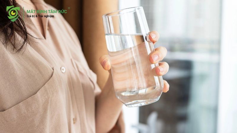Một người phụ nữ cầm ly nước lọc trong tay để bổ sung nước cho cơ thể.