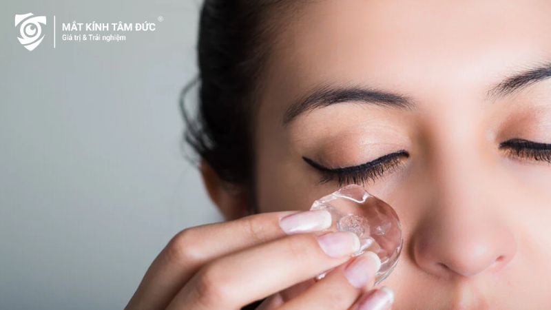 Một người phụ nữ đang sử dụng viên đá lạnh để chườm mắt, giúp giảm sưng sau khi khóc.