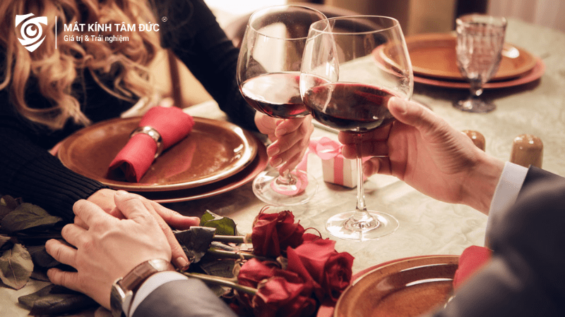 Một cặp đôi hạnh phúc ăn tối ngày Valentine, bữa tối lãng mạn với tông màu đỏ chủ đạo có rượu và hoa